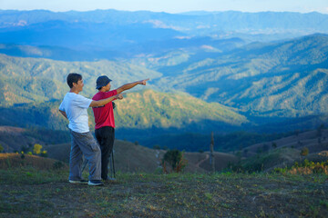 Asian Man is happy and relaxed with the scenery of the sea mist a beautiful natural in the morning at Car Camping site on the top of a mountain in winter season at Chiang Mai, Thailand.