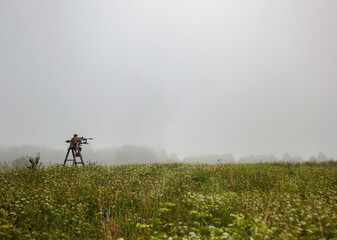 Hunter on mobile tower is waiting for the ungulates to appear out of the fog.