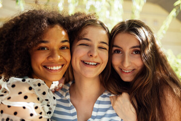 Closeup portrait of three pretty female teenagers of different nationalities in casual clothes are...