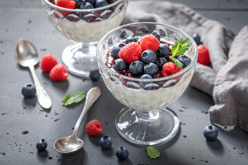Sweet and traditional Panna Cotta with raspberries and blueberries jam.