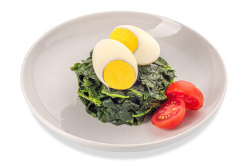 Spinach cooked with cut hard boiled egg and cut cherry tomato in white dish isolated