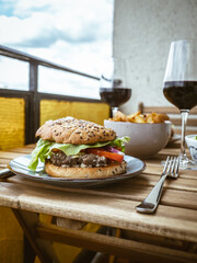 Table for a home dinner lunch date on a balcony with burgers fries salad and wine