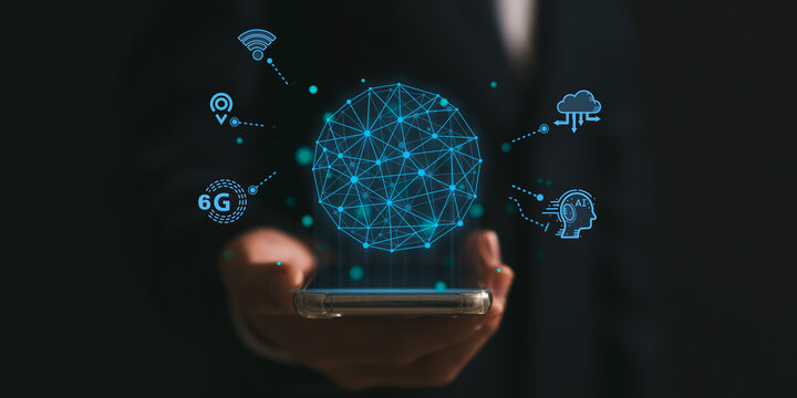 Businessman holding smartphone shows network digital hologram, AI and internet of things on 6G network wireless systems concept.