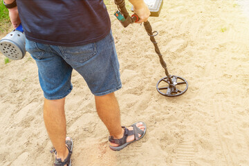 Rare view unrecognizable person using electronic metal detector and scoop to find treasures in the...
