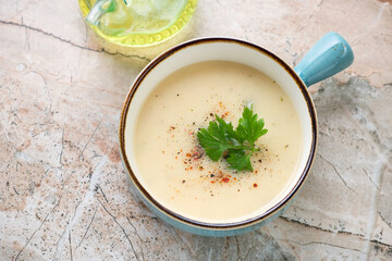 Turquoise serving bowl with cheese soup on a pinkish granite background, horizontal shot