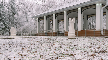 A place to play chess in the winter park. Chess pieces in the winter city park. A chess house and...