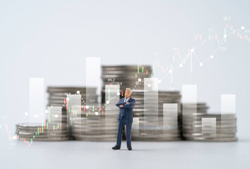 Businessman standing in front of coins stacking with stock market graph chart for  analysis...