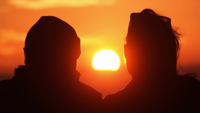 Silhouette of a couple watching the sea at sunset. Romantic love concept.