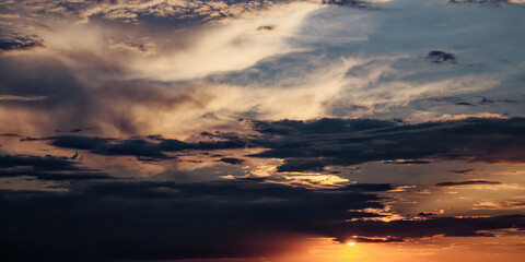 The sky filled with dark clouds and a shining sun at sunset.