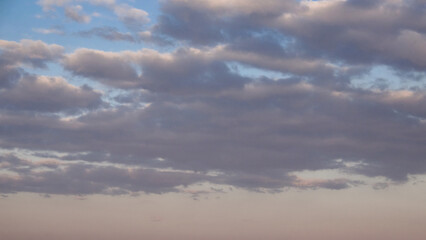 Obraz premium The image shows fluffy clouds against a soft blue sky during sunset.