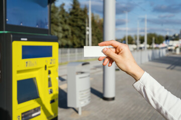 Selective focus on paper ticket in female hand against blurred bus station background