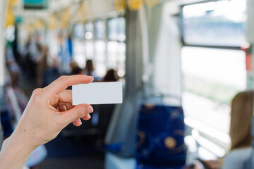 Selective focus on passenger hand holding ticket against blurred public transport interior