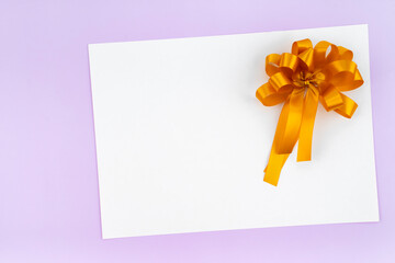 Golden ribbon on blank paper with purple background.