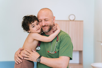 Warm embrace between a caring male doctor and a young boy in a clinic setting