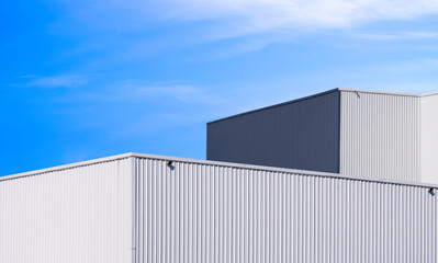 Modern white and gray aluminium industrial factory buildings against blue sky background, perspective side view with copy space