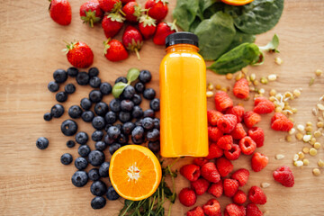 Citrus fruits, berries, greens, sprouted beans and bottle of orange juice