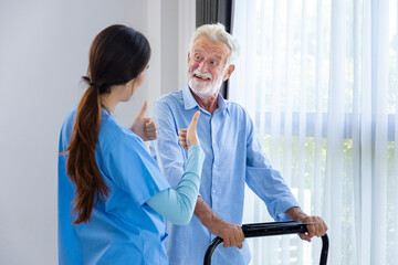 Hospice nurse is supporting Caucasian man to walk using treadmill in pension retirement center for...
