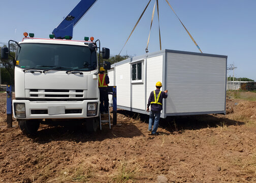 The Crane trucks transport the mobile office buildings or container site office for installation in the construction site area, project mobilization.
