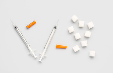 Sugar cubes with syringes for insulin injection on white background