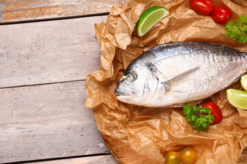 Raw dorado fish with lime and tomatoes on grey wooden background
