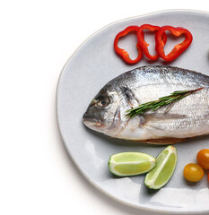 Plate of raw dorado fish with lemon and vegetables on white background