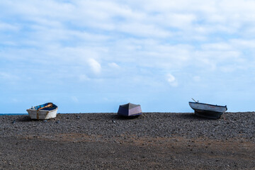 Serene Pebble Beach: Boats at Rest under a Partly Cloudy Sky