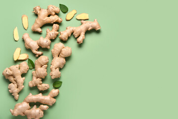 Fresh ginger roots and leaves on green background