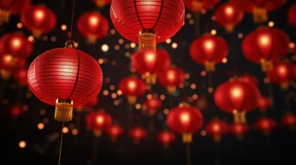 Poster Traditional red Chinese lanterns hanging against a dark background with glowing bokeh, festive and cultural decor. © tashechka