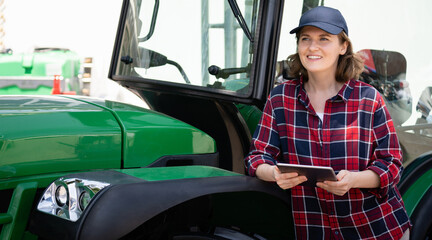 Woman farmer with a digital tablet and green agricultural tractor © scharfsinn86