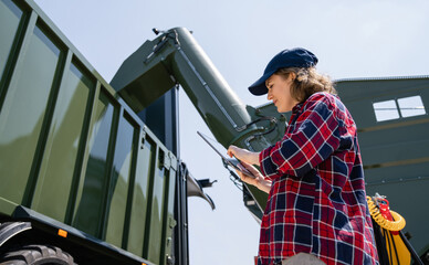 Woman farmer with tablet watching grain loading