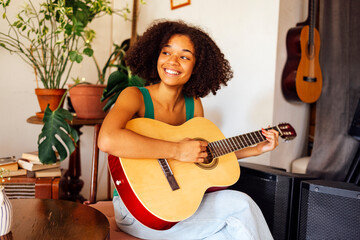 Afro americal young woman playing acoustic guitar.