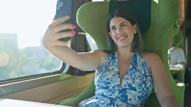 Carefree hispanic woman captures smiling selfie on her urban train journey