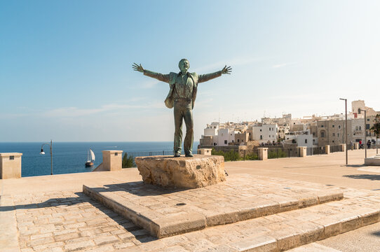 Polignano a Mare, Puglia, Italy - October 4, 2023: Bronze sculpture to Domenico Modugno, Italian musician and politician, on the seafront in Polignano a Mare.