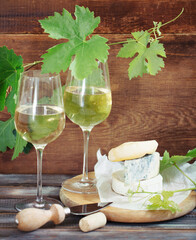 Glasses of white wine, bottle and cheese