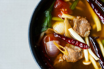 Top view of Tom Yum Pork and spicy soup.Food of Thailand consists of pork, dried chilies, tomatoes,...