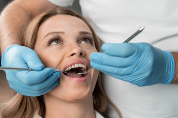 In the dental chair, a woman happily demonstrates her new smile, which she received thanks to the...