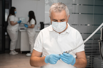 The senior dentist prepares the instrument for the appointment. The team of dentists collaborates...