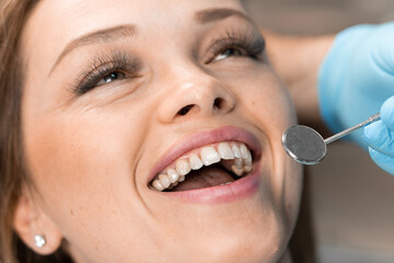 The dentist carefully works on the patient's smile, creating the perfect balance between aesthetics and health. In dental chair, patient confidently maintains dialogue about taking care of her smile.