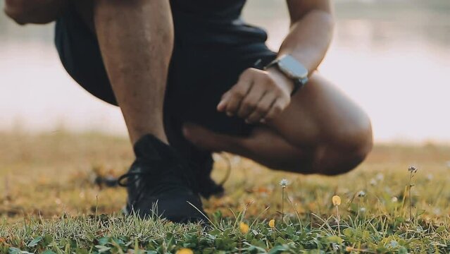 Attractive young man stretching in the park before running at the sunset focus on shoes