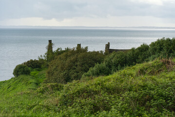 Alte Häuser hinter Sträuchern am Gobbins Cliff