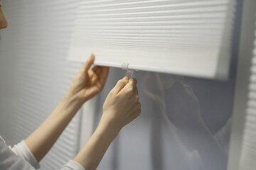 Close up of woman opening window blinds