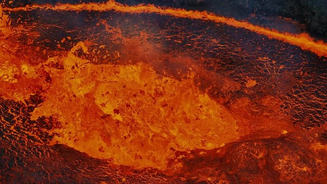 Unique close up view of red hot lava exploding, boiling, and bubbling in the volcano crater, drone shot. Volcanic eruption, natural hazard, and disaster concepts.