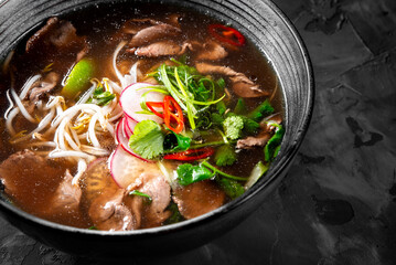 Soup Pho Bo in bowl on gray stone table