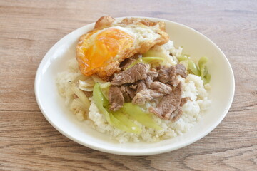 spicy stir fried slice beef meat with long sweet chili and onion on rice topping egg in plate 