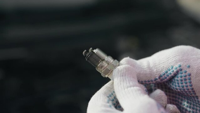 Close up A mechanic compares a new and old burnt-out spark plug that led to a misfire, Increased fuel consumption and an error in check engine