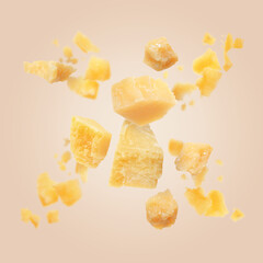 Tasty parmesan cheese falling on dark beige background