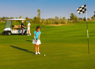 Sportive family playing golf on a golf course