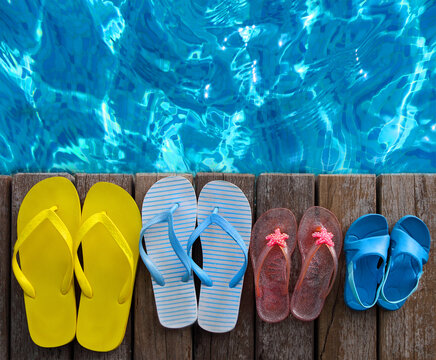 Brightly colored flip-flops on wooden background near the pool