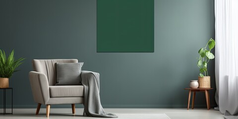 Dark green blanket on grey sofa in bright living room with empty poster and armchair.