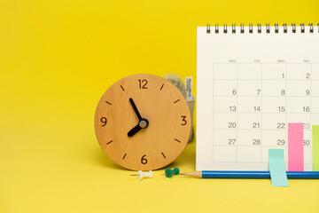Fototapeta na wymiar close up of calendar and clock on the yellow table background, planning for business meeting or travel planning concept